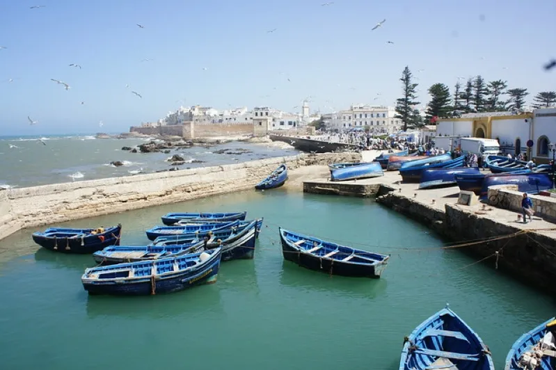 Boats are docked in calm waters near the shore, showcasing the beauty of best moroccan beaches.