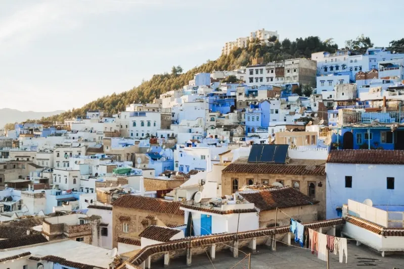 A scenic view of Chefchaouen, Morocco, showcasing its iconic blue buildings and mountainous backdrop.