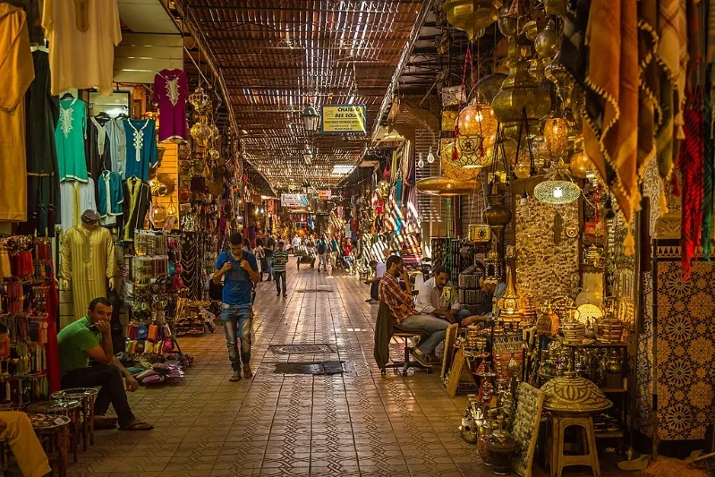 A bustling narrow alleyway in Morocco, lined with shops and filled with people exploring cultural treasures. 