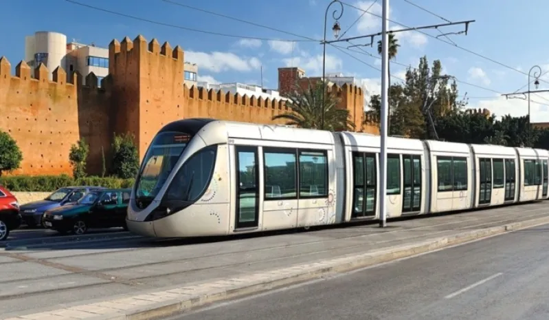 A tram moves down a street adjacent to a castle, illustrating the blend of modern transport and Morocco's rich history. 