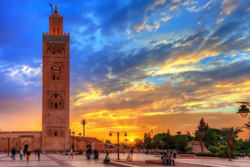 A stunning sunset in Morocco, featuring a clock tower silhouetted against the vibrant sky, perfect for travel inspiration.