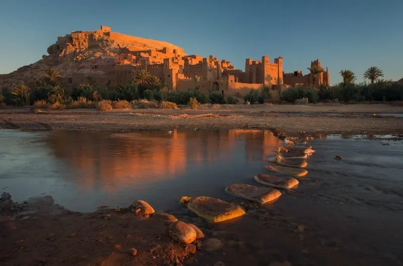 A stunning sunset reflects on water at the desert's edge, showcasing the beauty of cultural morocco tours. 