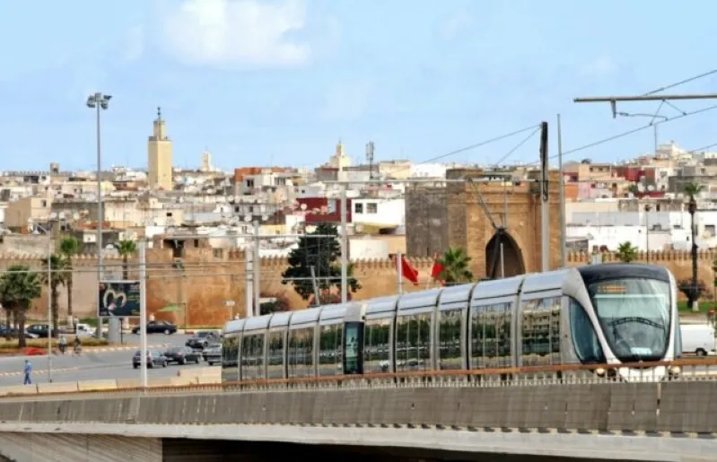 A train crosses a city bridge, showcasing urban transport options in Morocco. 