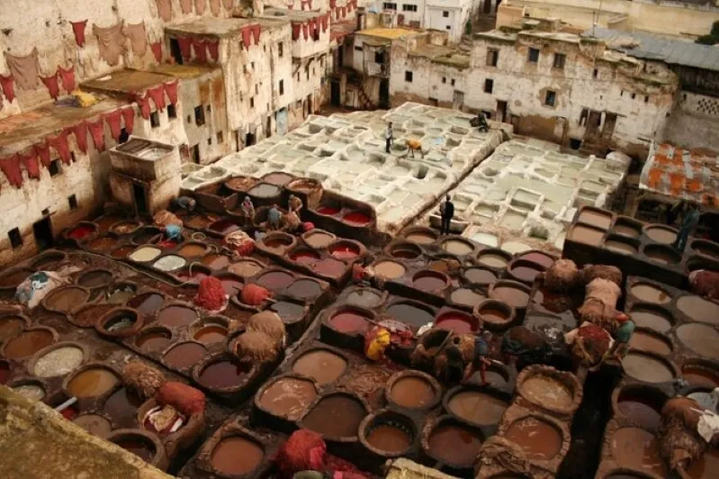 A vibrant depiction of fes morocco tour where crowds mingle among traditional pots, reflecting the city's dynamic atmosphere.