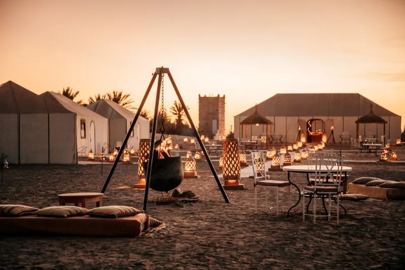 A tent featuring a swing and a fire pit, nestled in the sand, showcasing a tranquil outdoor setting live in morocco.