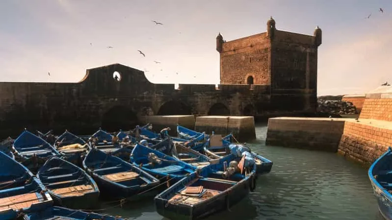 Scenic view of blue boats in a city harbor, highlighting the beauty of a morocco travel package.
