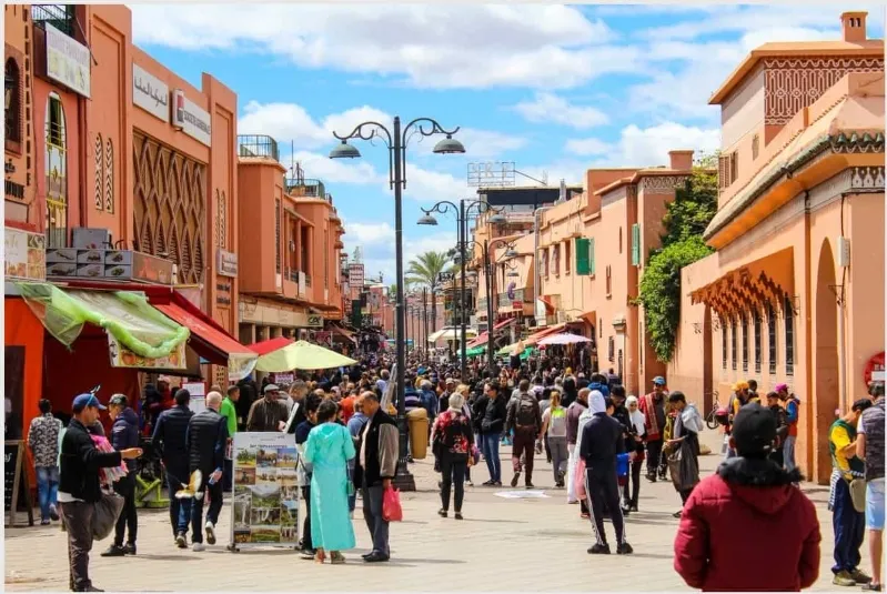 A bustling Moroccan street filled with people walking, showcasing the vibrant life and culture of the region.