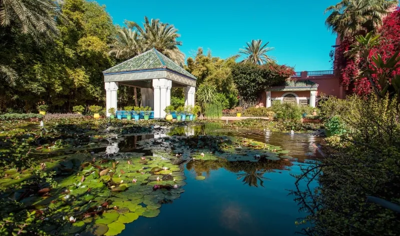 Lush garden of the Alhambra Palace in Marrakech, Morocco, showcasing vibrant flora and serene pathways for travelers. 