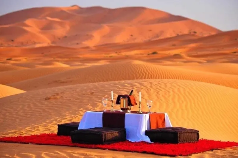 A romantic desert scene featuring a table and two chairs, perfect for intimate dining during Morocco private desert tours.