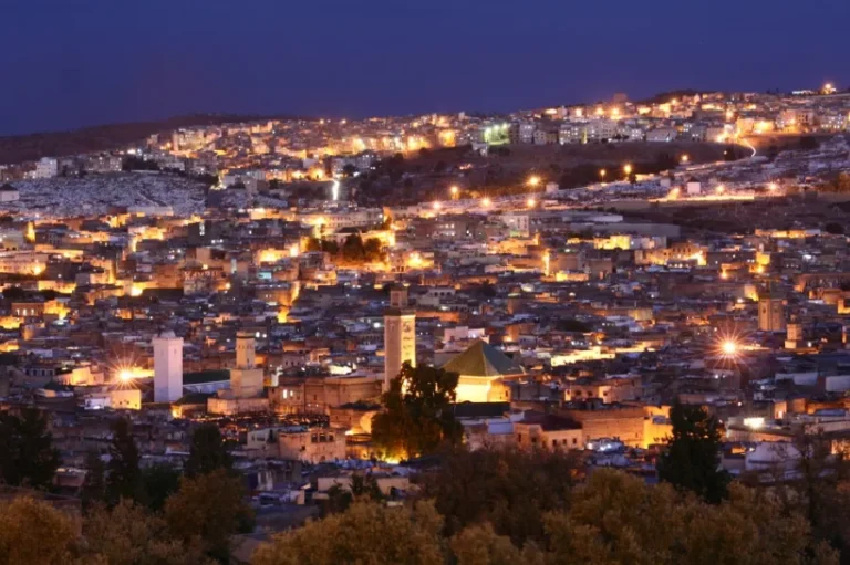 A nighttime view of Jerusalem, showcasing its illuminated skyline and historic architecture against a dark sky.