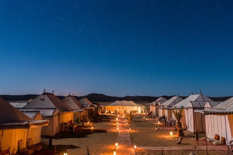 Illuminated tents in a luxury camp under the starry night sky of the Moroccan desert.