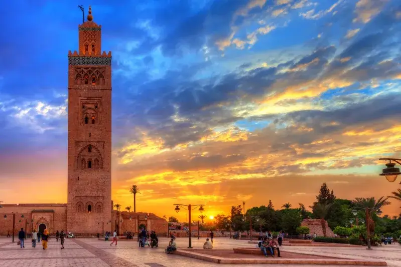 A picturesque sunset in Morocco, featuring a clock tower in the foreground, showcasing the beauty of Family Morocco Tours. 