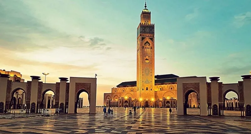 The mosque's clock tower illuminated at sunset, showcasing Morocco's stunning architecture for travelers. 