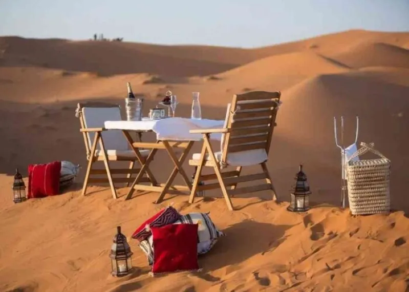 A romantic dinner set in the desert, featuring elegant table settings under a starlit sky, showcasing Morocco's enchanting beauty.