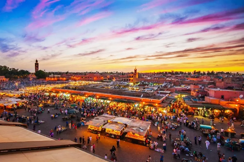 A stunning sunset over Marrakech, showcasing the city's vibrant colors and architecture, with hints of Chefchaouen day trips.