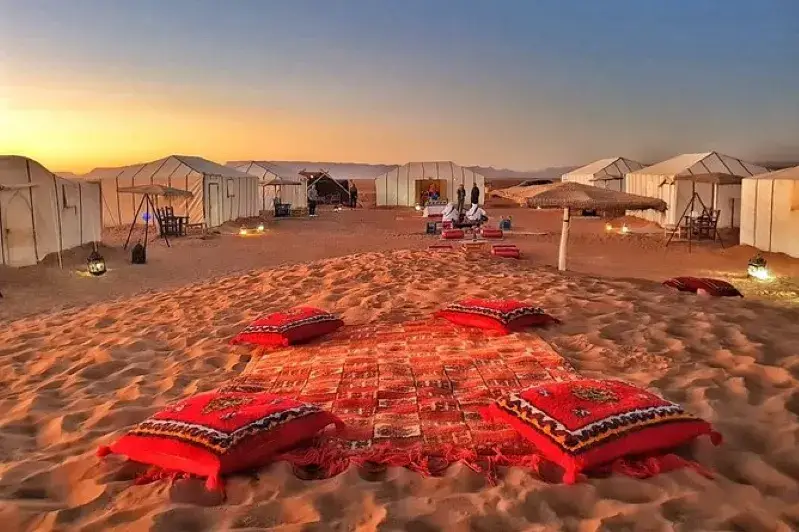 A desert landscape featuring tents and a colorful rug, showcasing the essence of Family Morocco Tours.
