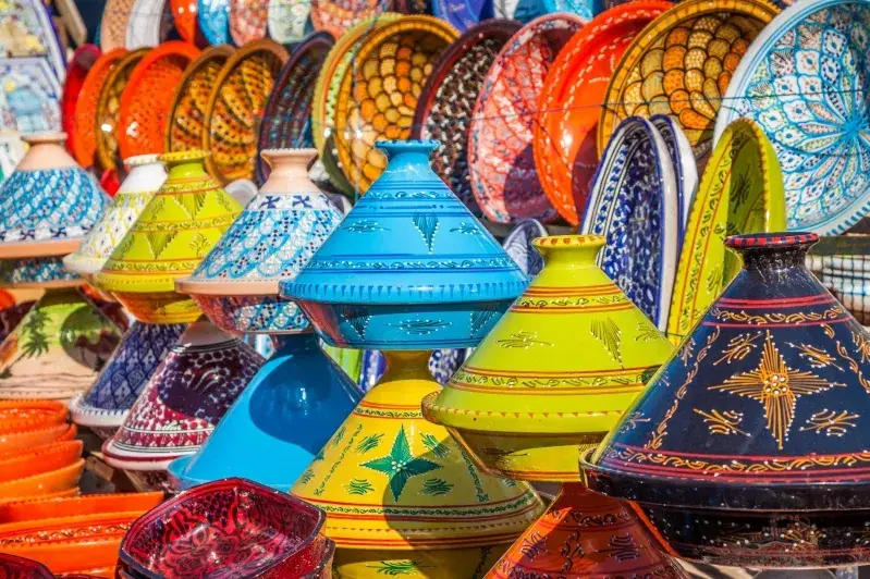 Colorful pottery displayed for sale at a Moroccan market, showcasing vibrant designs and craftsmanship. Imperial Cities Tours Morocco.