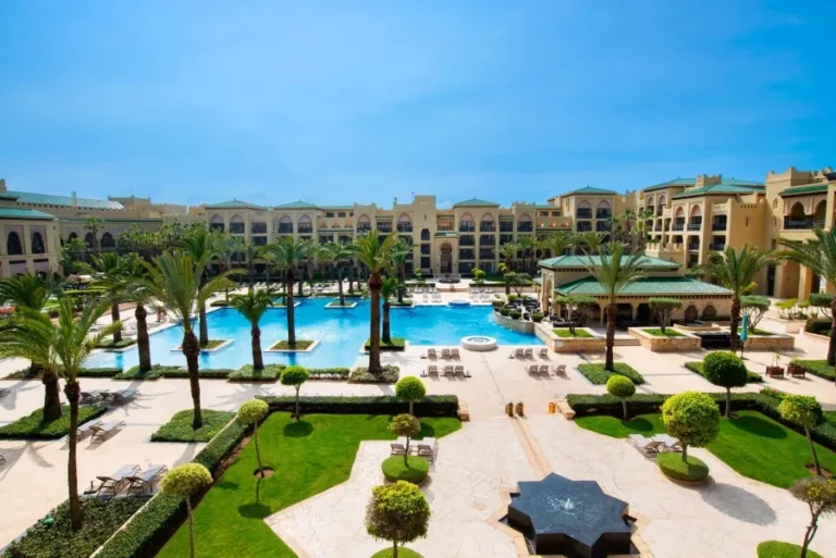 A serene view of the hotel pool and lawn area, showcasing the luxurious ambiance of a Moroccan resort.