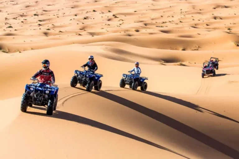 A group of four adventurers rides quad bikes through the expansive sands of the Sahara Desert in Morocco.