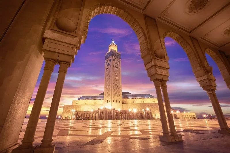 A mosque illuminated by sunset, showcasing intricate architecture, symbolizing Moroccan culture and travel experiences.