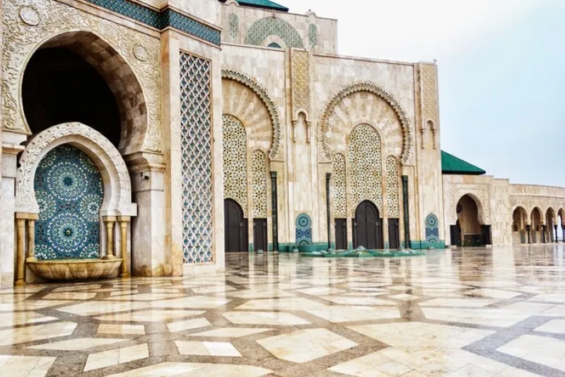The interior of a grand mosque featuring elegant arches and vibrant green tiles, showcasing intricate architectural beauty.