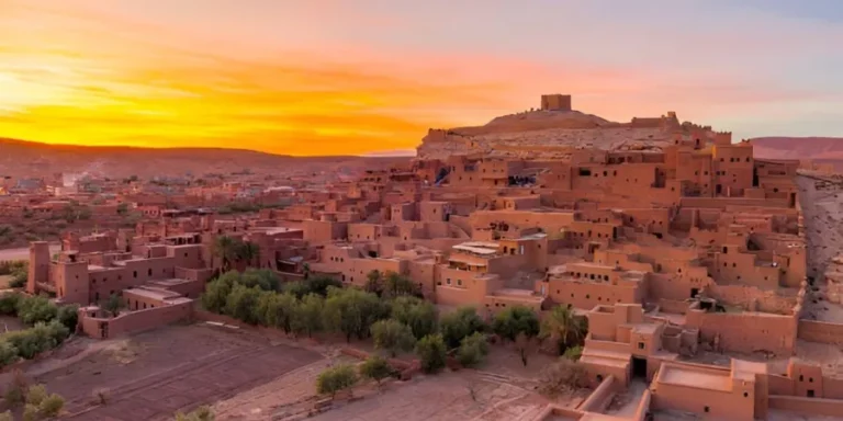 A stunning sunset casts vibrant colors over the desert village of Atdhe, highlighting the beauty of Ouarzazate's landscape.