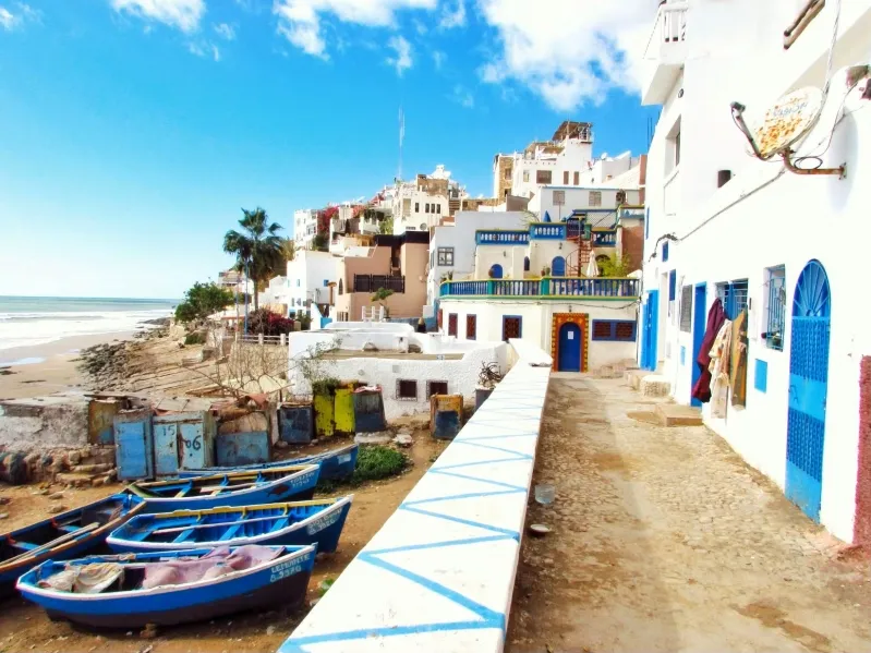 Scenic view of a beach with boats in the town, highlighting popular day trips from Malaga to Morocco.