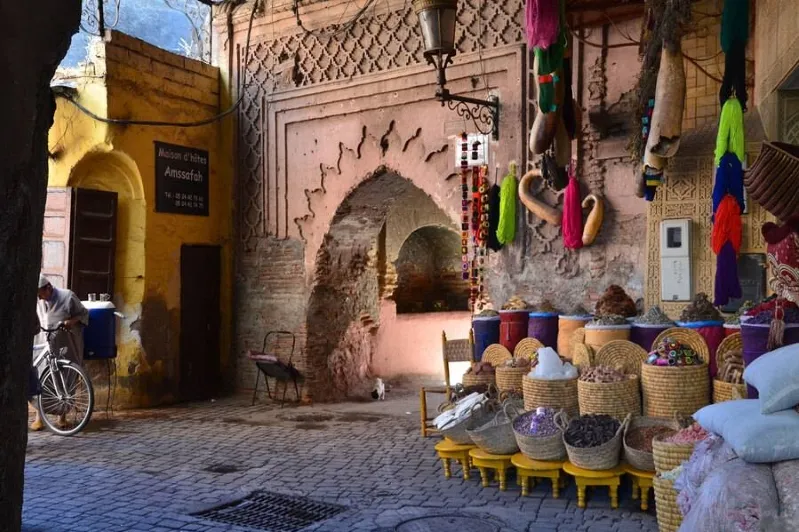 A vibrant street in Morocco featuring colorful baskets and a parked bicycle, showcasing local culture and craftsmanship.
