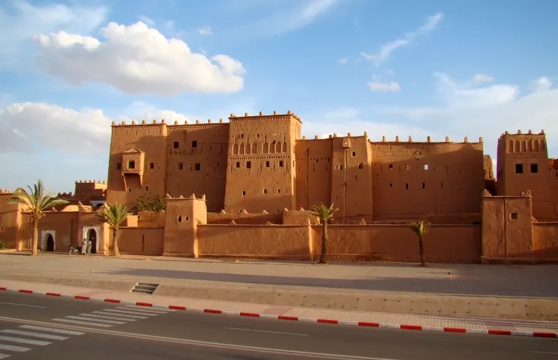  A large brown building with numerous windows, promoting tour packages to Morocco.