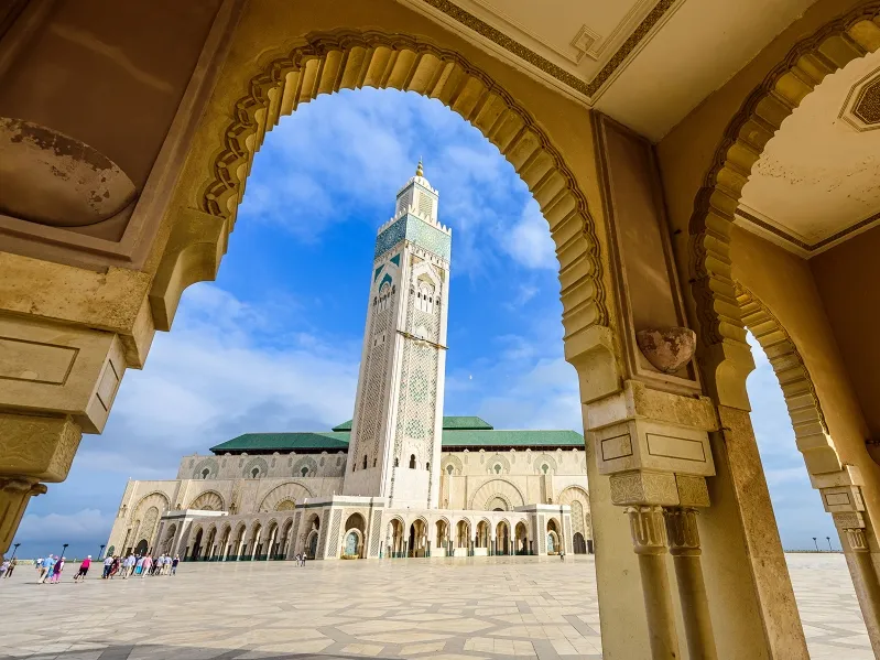 View of a mosque framed by an archway, showcasing intricate architecture during a Morocco group tour.