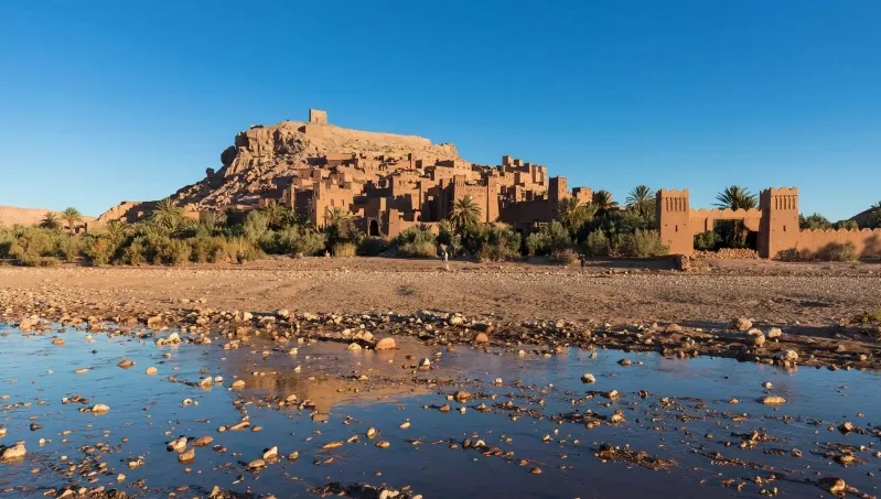 A panoramic view of a desert landscape featuring the ruins of an ancient city, highlighting the beauty of Morocco's history.