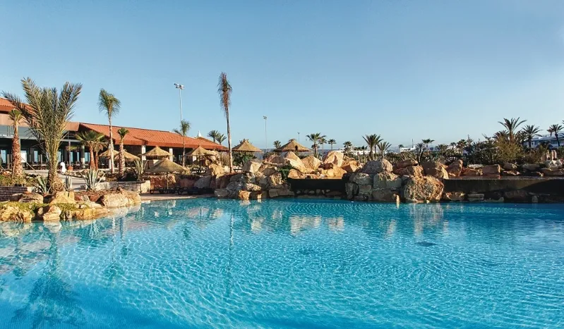 Spacious pool featuring a rock wall and lounge area, perfect for enjoying all inclusive vacations to Morocco.
