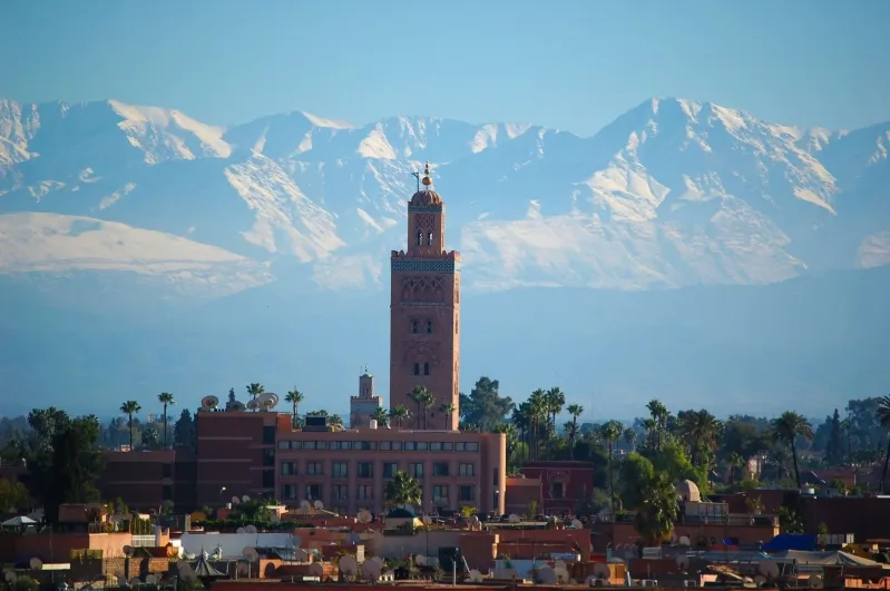 Marrakech cityscape with snow-capped mountains in the background, showcasing Morocco travel tour operator.