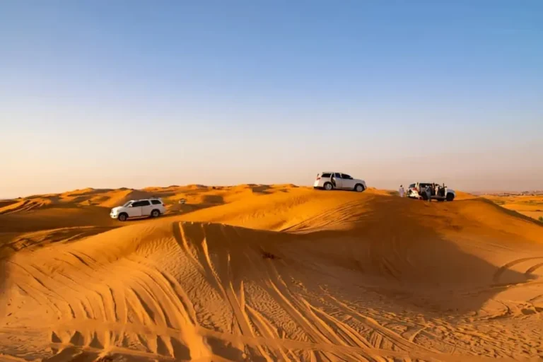 Four vehicles parked on sand dunes in the desert, showcasing an adventurous scene for all-inclusive vacations to Morocco.