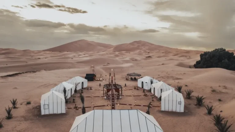 A desert camp featuring several tents, including a prominent white tent, showcasing a unique experience with top Morocco tour operators.