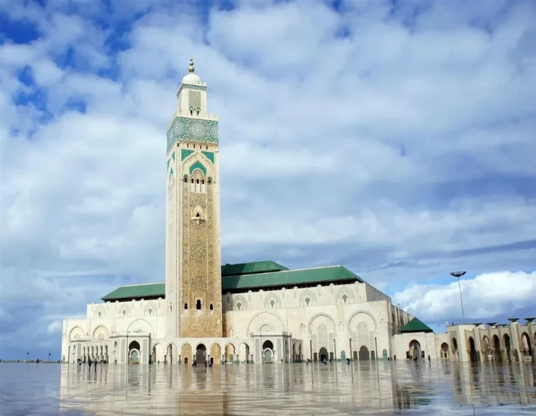 A mosque surrounded by water features a prominent clock tower, ideal for small luxury tours in Morocco.