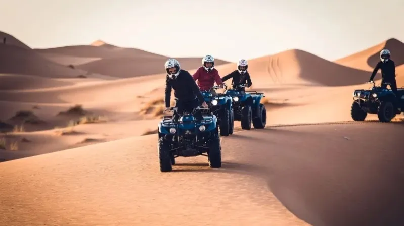 Four people riding ATVs through the desert, showcasing an adventurous tour experience in Morocco. 