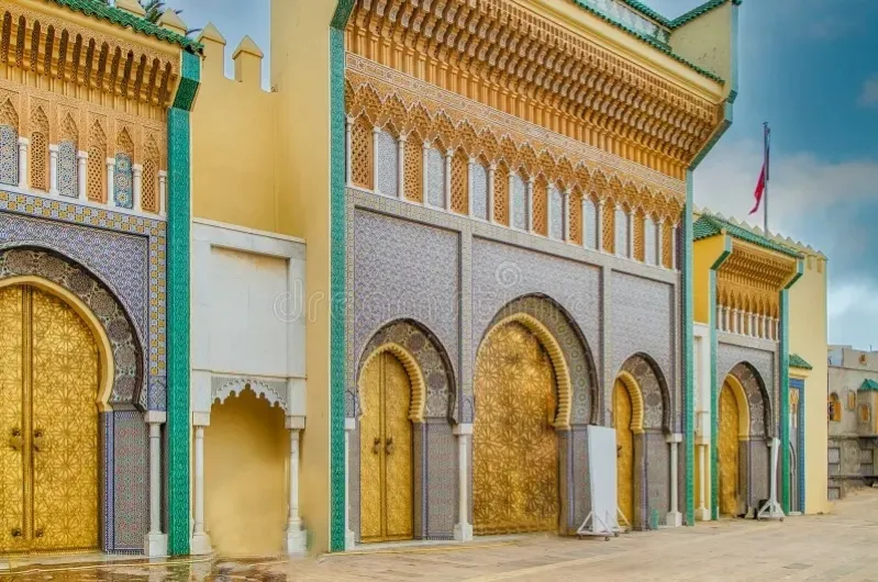 The grand entrance to the Sultan of Morocco's palace, showcasing intricate architecture and Moroccan people nearby. 