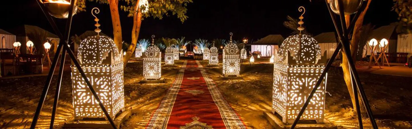 Luxury New Year’s Eve desert camp in Morocco with tents, fireworks, and Sahara dunes at night